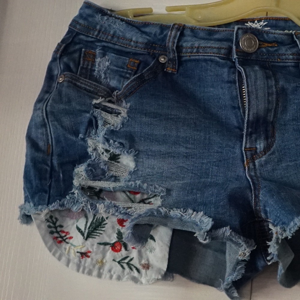 ripped denim shorts with design on the pockets